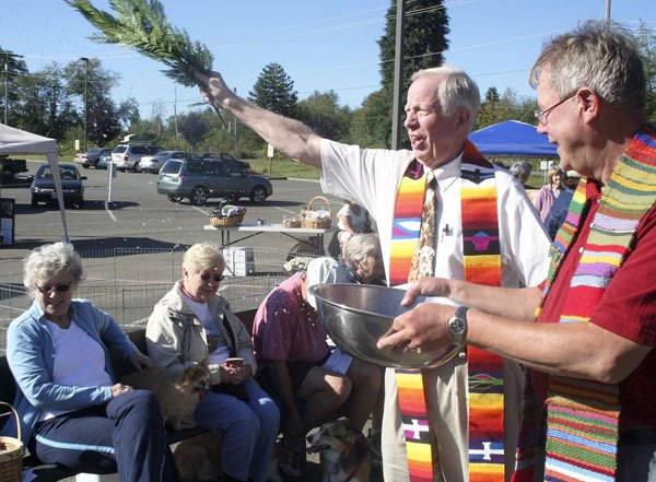 Pastor Orv Jacobson blesses the animals by dousing them with water from a palm branch dipped into a pan of water held by Pastor George Larson. This year’s event attracted around 60 pets