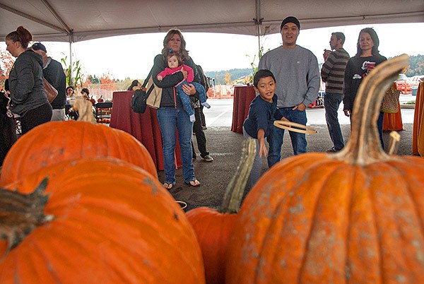 Noah Sio of Silverdale tosses a wood ring toward a bunch of pumpkins while playing a game Oct. 25. Behind him is his father