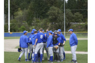 The Olympic baseball team huddles between innings during Wednesday’s 8-3 win against Kingston. The Trojans are tied with North Kitsap for first place among Class 3A teams in the  Olympic League. Both teams have two games remaining.