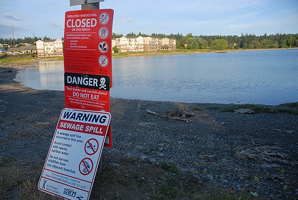 Signs warn of a sewage spill in Dyes Inlet Aug. 3.