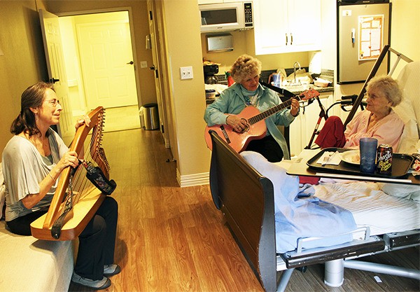 Judy Friesem and Carole Glenn visit with Hospice patient Naomi Murphy. Both Friesem and Glenn offer music therapy as a service to patients at the care center in Bremerton.