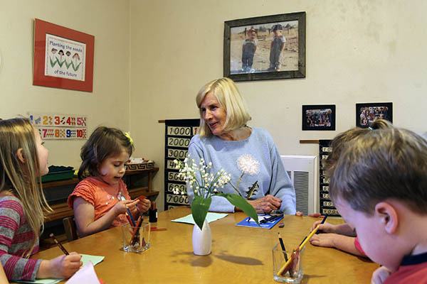 Barbara Rhoe assists students with their studies at The Farm Montessori preschool and kindergarten on May 12. Rhoe is retiring after 40 years.