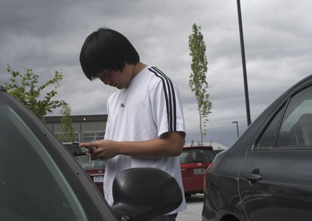 Kevin McVicker pauses to send a text message before stepping into his car Tuesday afternoon in Silverdale. Although the teen won’t text while driving