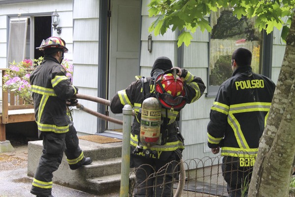 Poulsbo firefighters remove a hose from a house at 900 NW Rasmussen Court
