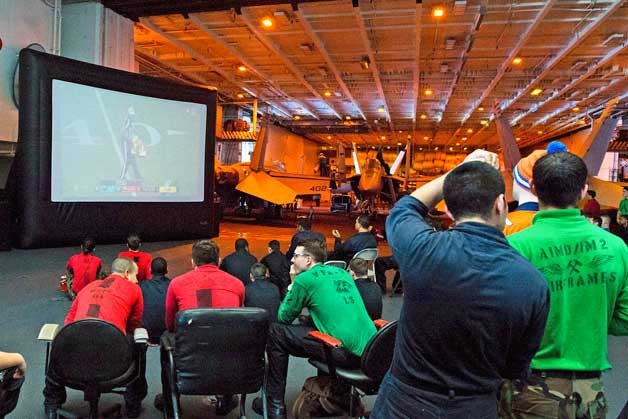 Sailors aboard USS John C. Stennis (CVN 74) watch Super Bowl 50 between the Carolina Panthers and the Denver Broncos in the hangar bay.