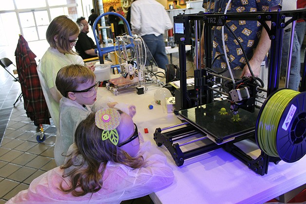 Children stand near the Kitsap Robotics and Electronics Enthusiast Group booth to watch a 3-D printer in action. The booth was a part of the West Sound STEM Showcase event on Saturday.