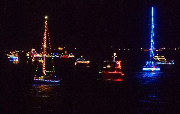 Boats with the Bremerton Yacht Club sail past the Silverdale Waterfront Park pier during BYC's annual Lighted Boat Parade Dec. 19. Several dozen people stood on the pier in the cold