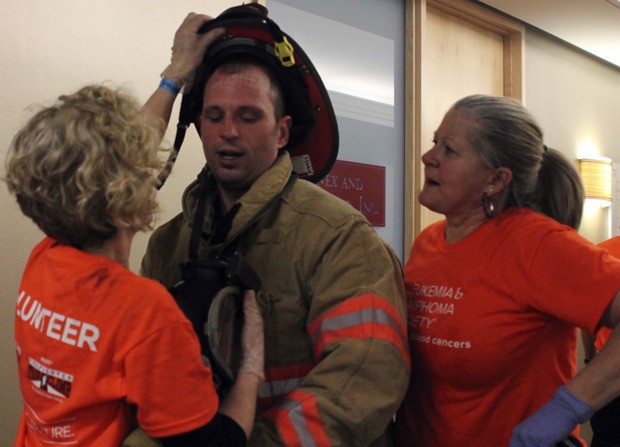 Bremerton firefighter Brian Marceau gets some help removing his bunker gear after climbing 69 flights of stairs in 16 minutes and 31 seconds on Sunday.