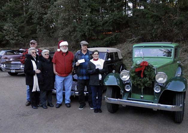 Members of the Olympic Vintage Auto Club pose with their vintage vehicles while giving the CK Food Bank a donation.