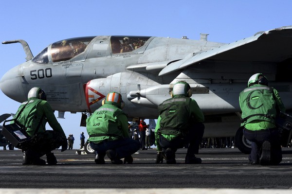Sailors stand by as an EA-6B Prowler from the Wizards of Electronic Attack Squadron (VAQ) 133 prepares to take off from the flight deck aboard the aircraft carrier USS John C. Stennis (CVN 74). John C. Stennis is deployed to the U.S. 5th Fleet area of responsibility conducting maritime security operations