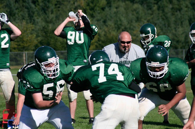 Klahowya Secondary School football coach Lyle Prouse watches as three linemen practice blocking Monday.