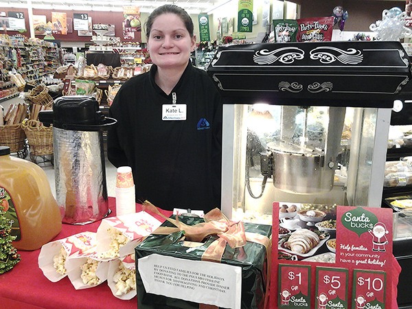Albertsons courtesy clerk Kate Long hands out free cider and popcorn at the Albertsons in Poulsbo Village