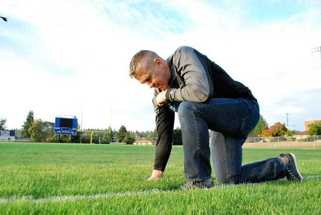 Coach Kennedy kneels in prayer at the 50-yard line of the Bremerton High School football field.