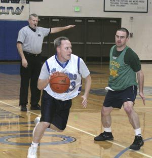 Oly girls hoops coach Rick Peters drives around Deputy Alan Languth in the Trojans 69-61 win on Wednesday.