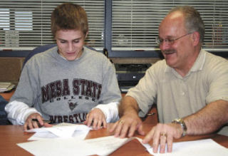 Bremerton wrestler Billy Richardson gets a hand from dad Bill as he signs his letter of intent to hit the mats for Mesa State College in Colorado.