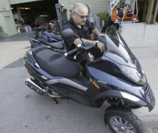 Cliff’s Cycle Center salesman Jim Gagnon checks over the new three-wheel Piaggio MP3 scooter at the Bremerton store.