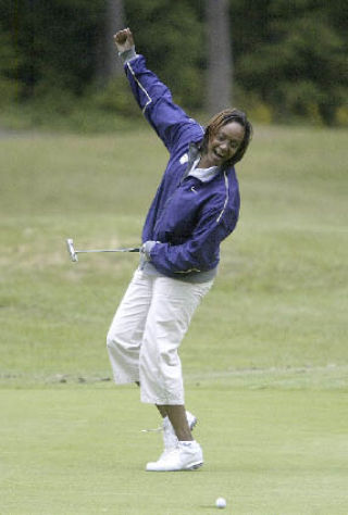 University of Washington women’s basketball coach Tia Jackson tries to help her make its way into the cup on the 10th hole at McCormick Woods.