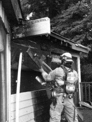 Central Kitsap Fire & Rescue firefighter Steve Whitish checks for hot spots under the eaves of a home on Tanda Avenue NW in Chico that caught fire Tuesday.