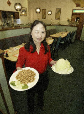 Golden Mum Restaurant co-owner Amy Lin holds up two of the new authentic Chinese dishes she and her husband