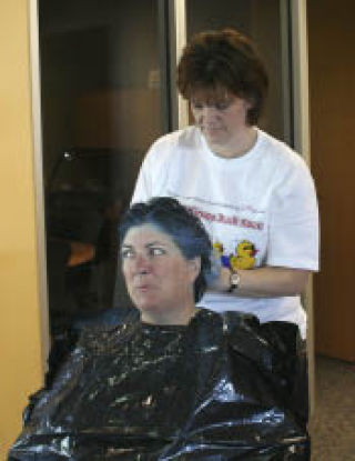 American Marine Bank Silverdale branch manager Mary Hoover sits quietly as bank operations officer Mechelle Hoerer sprays her hair blue. Hoover