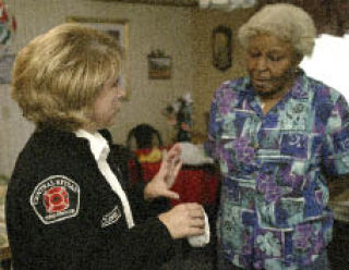 CKFR spokeswoman Theresa MacLennan (left) speaks with Gerlena Kingston about the new smoke alarms the fire agency installed in her East Bremerton home Tuesday.