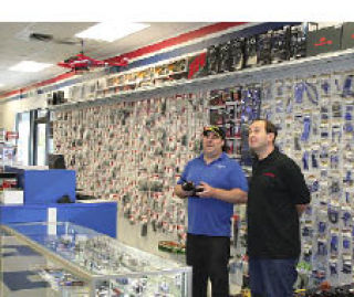 Silverdale HobbyTown USA co-owner Jonathan Rosen (right) looks on as store manager Marty Gundran flies a Blade CX2 helicopter in the shop.