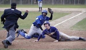 Olympic catcher Bryan Deszell holds up the ball while he and North Kitsap's Stephen Tucker watch the umpire call Tucker out at the plate in the Trojansâ?? 7-6 win Friday.