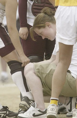 South Kitsap High School teacher and assistant athletic medicine trainer Ryann Springer inspects a softball player's knee during a game last week. She was arrested Tuesday for sexual misconduct.