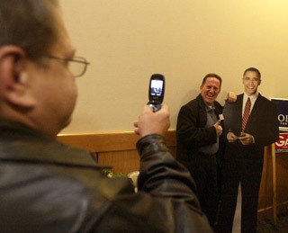 Michael Willis snaps a photo on his cell phone of his friend Jeff Bassett posing with a cutout of Barack Obama at the Democrats' election party Tuesday night at Silverdale Beach Hotel.