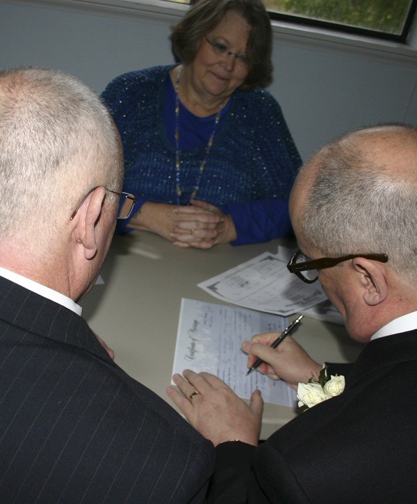 Greg Nolan and Bill Trombley sign their marriage certificate.