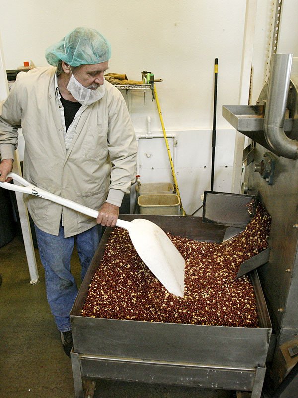 Roaster Duane Carroll spreads a fresh batch of peanuts in the CB’s Nuts building off Bond Road.