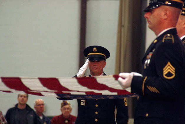An Honor Guard prepares a flag for John “Bud” Hawk’s daughter Monday during a memorial service at the fairgrounds.