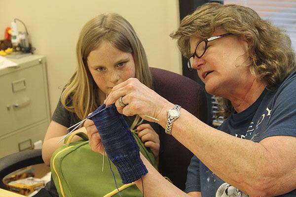 Penny Garner shows Poulsbo Elementary School student Rebecca Kofol the technique for knitting socks May 16