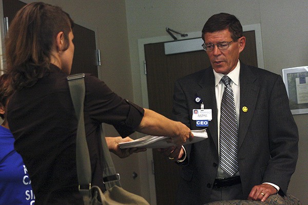 A canvasser hands Harrison Medical Center CEO Scott Bosch about 1