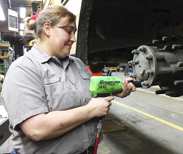 Maurine Simons works on a school bus wheel hub and is preparing it for installation of a tire.