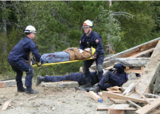 Kitsap County technical rescue team members pull a “victim” from a rubble pile outside Klahowya Secondary School Monday. Police