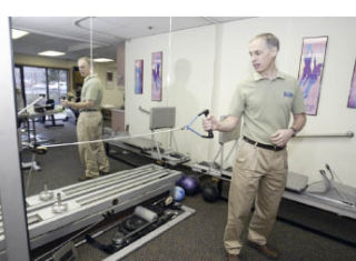 Kitsap Physical Therapy co-owner Mike Danford explains how to use an impulse machine. The physical therapy practice is celebrating 30 years in business.