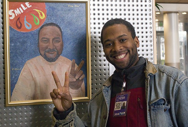 Real Change News vendor Vaughn Snoddy Taylor poses with a portrait of Jonas Stone