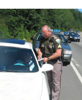 Kitsap County Sheriff’s Sgt. Mike Merrill writes a ticket to a driver as cars whiz past him in the right lane. Many drivers are unaware of the “Move Over Act” which was made a law in 2005 and requires drivers
