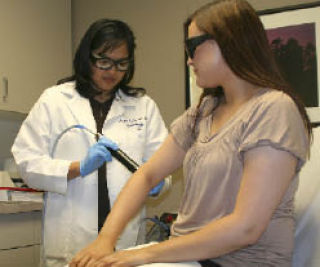 Tje Doctors Clinic Board Certified Dermatologist Dr. Irene Buño (left) demonstrates the PHAROS EX-308 on clinical aesthetician Layla Dalton. The device treats skin diseases including psoriasis