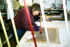 Neon artist Laurie Lewis marks a bend on what will be a neon snake. Glass tubes in the foreground await their fate.