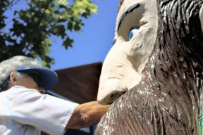 Hansville resident Jean Stange works on one of the carved statues at George’s Corner. She was in a group that repainted the popular statues.