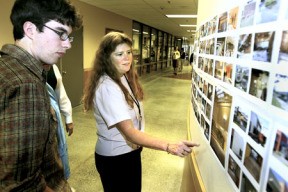 Poulsbo Junior High office secretary Kimberly Demming shows Bryan Harthorne the wall of progress at the opening dedication ceremony Thursday. The photo montage documented the construction progress.