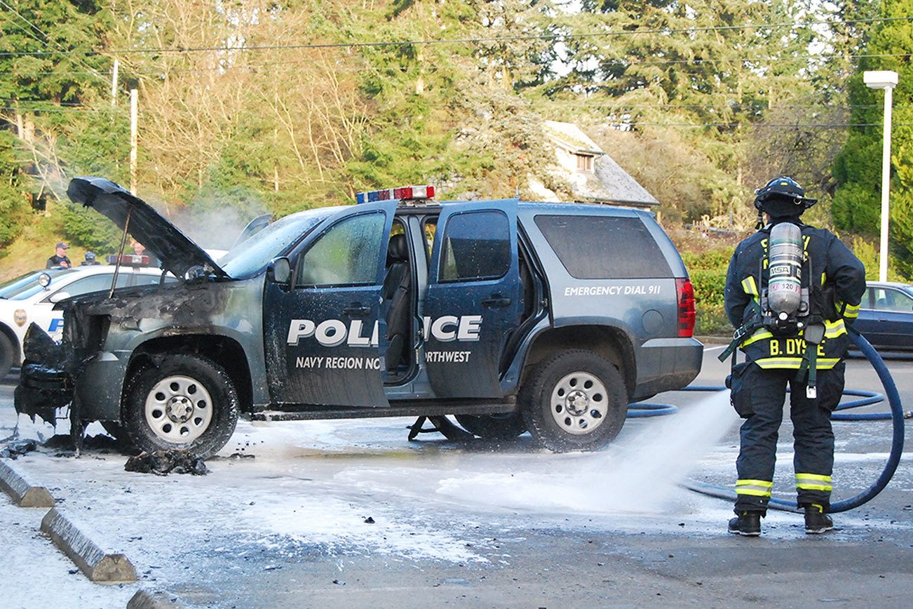 A South Kitsap Fire and Rescue firefighter cleans up after an engine fire that destroyed a Navy Region Northwest Police vehicle Dec. 14 in front of the Shell Food Mart at the intersection of Mile Hill Road and Woods Road. Firefighters sprayed water and foam to extinguish the fire. Bob Smith | Kitsap News Group