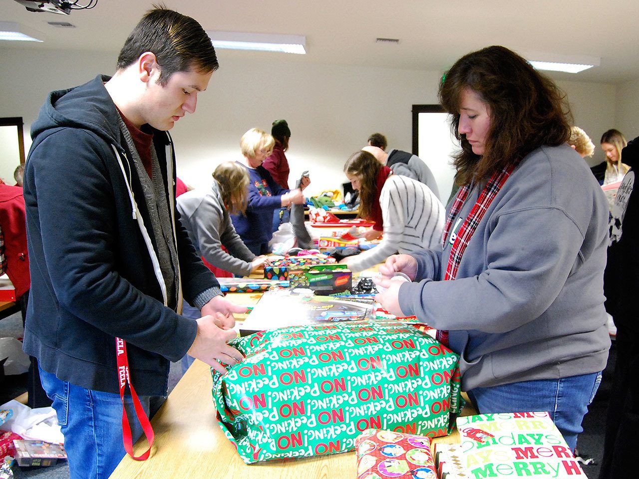 Austin Gese (left) and Laura Gese wrap presents inside the South Kitsap Fire and Rescue’s Tremont station Saturday, Dec. 17. Family member John Gese serves as co-chair for the event. Bob Smith | Kitsap Daily News photo
