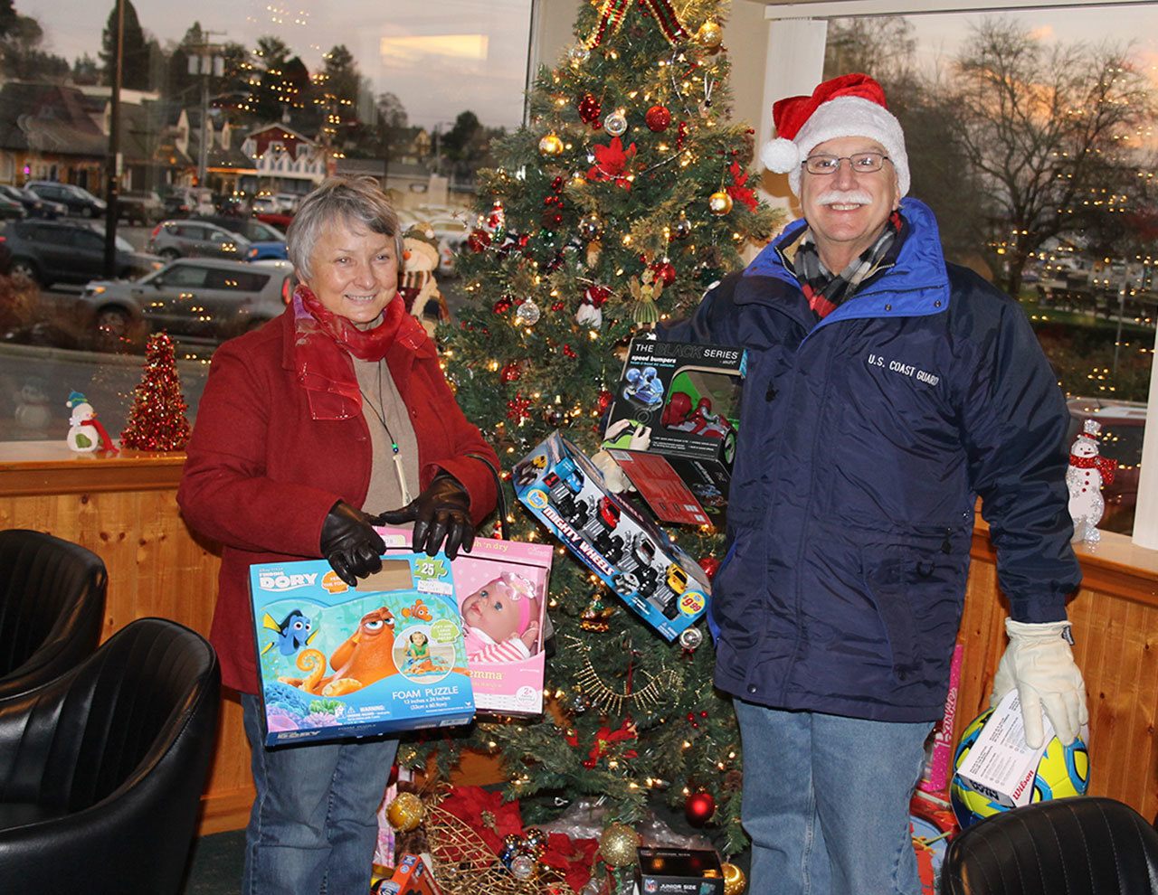 Tina McFee and Al Aicher of ShareNet pick up toys — and a check for $6,200 — from the Sons of Norway lodge in Poulsbo, Dec. 16. (Richard Walker/Kitsap News Group)