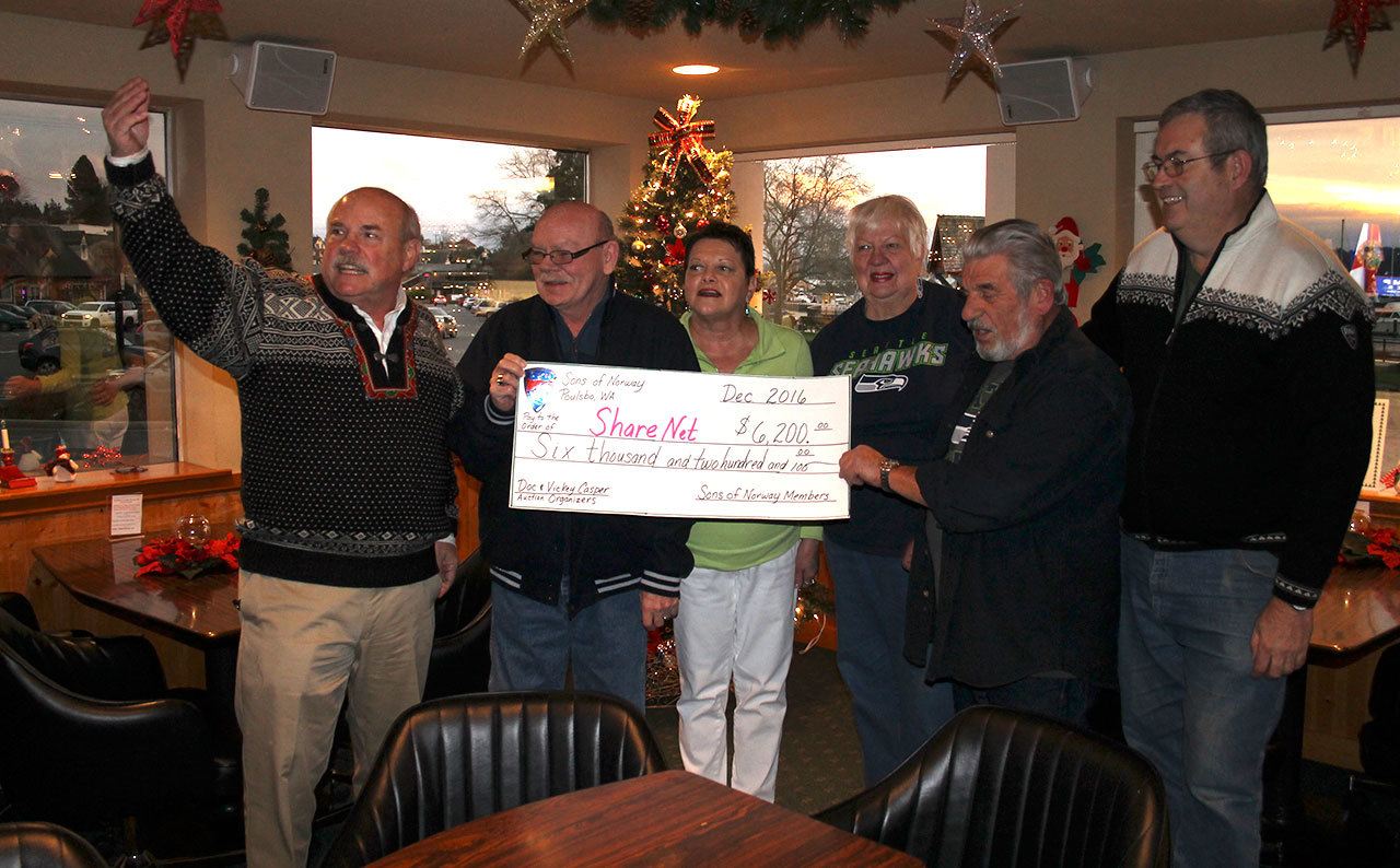 Sons of Norway lodge President Glen Robbins, with hand raised, calls Al Aicher and Tina McFee of ShareNet to join the photo Dec. 16 at the lodge. The lodge donated $6,200 and food and toys to ShareNet. (Richard Walker/Kitsap News Group)