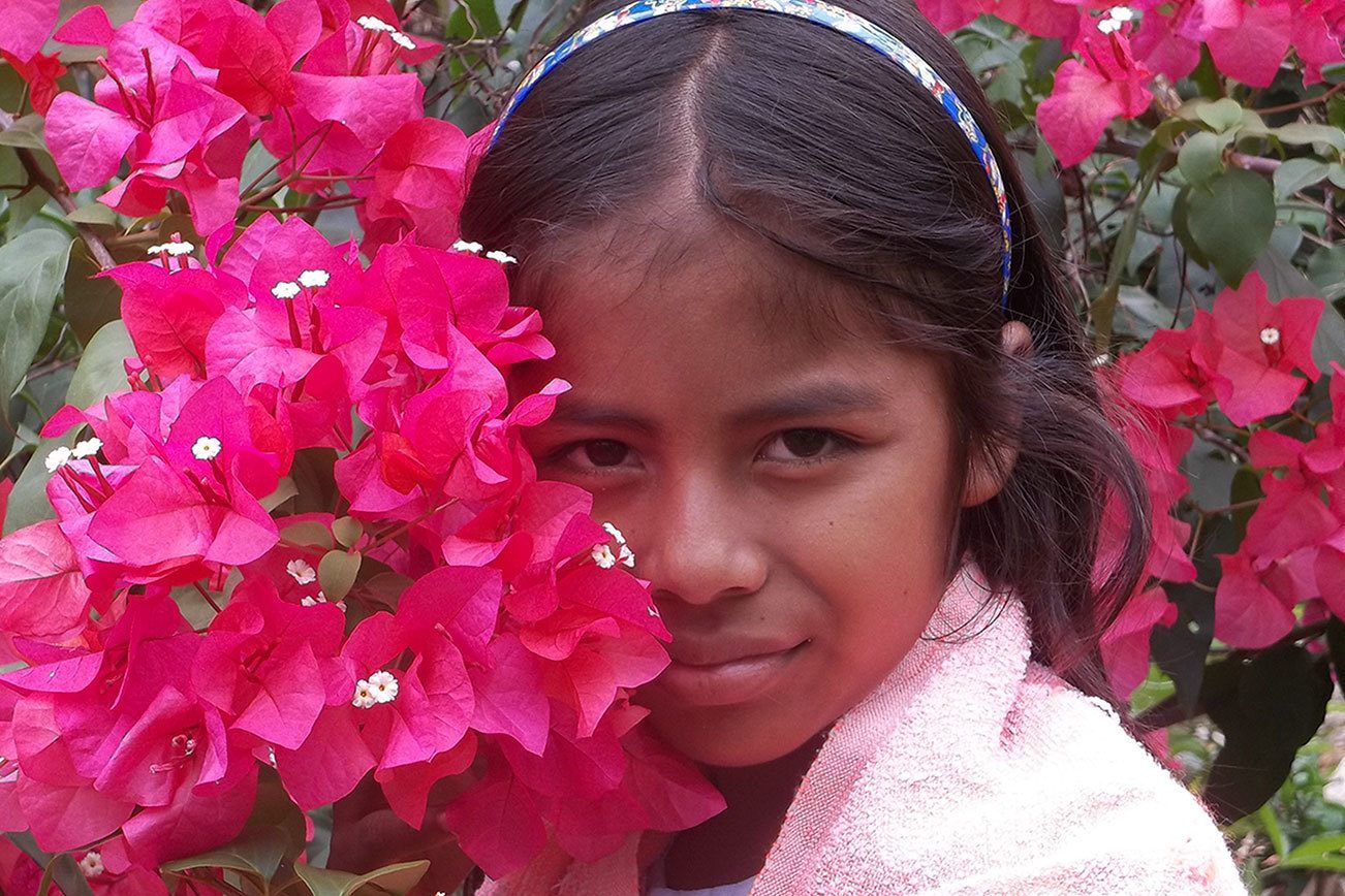 A girl named Wendy poses with flowers in this image from the Ometepe children’s photography project.