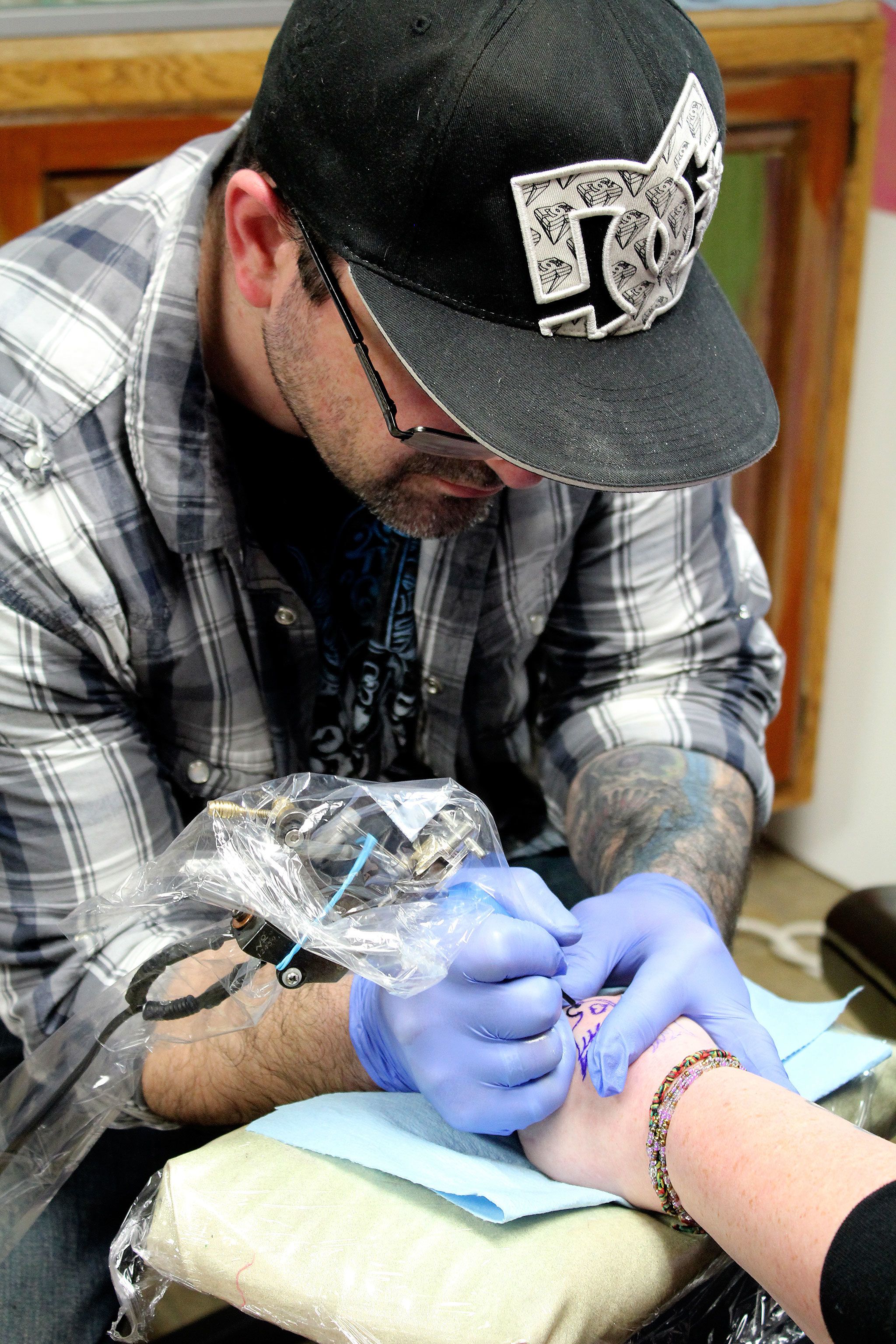 Eric Flint begins tattooing a turtledove on Amber Coe at The Clinic Tattoo on Valentine’s Day.                                Michelle Beahm / Kitsap News Group