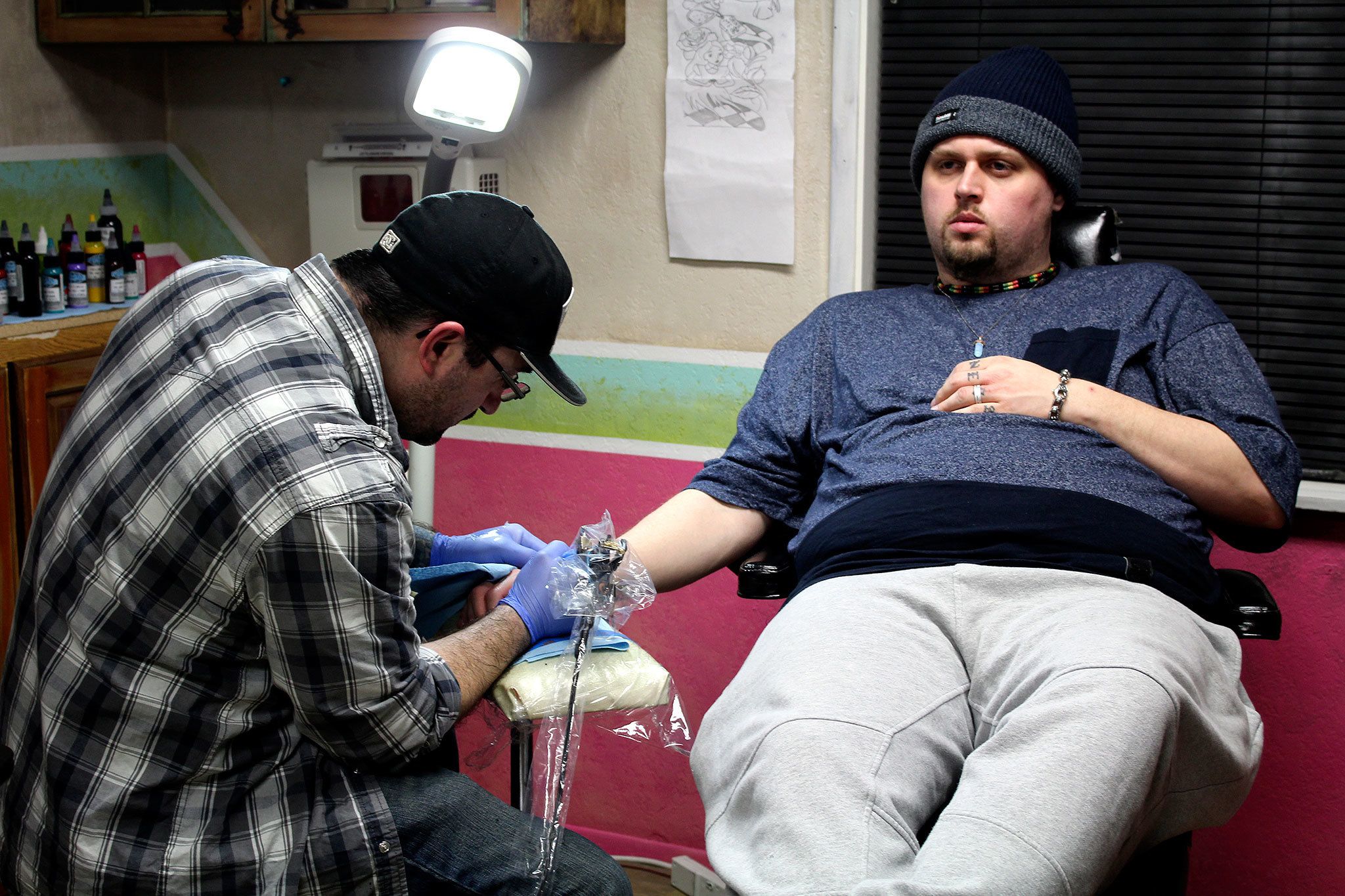 Eric Flint starts work on Corey Phillips’ flash art tattoo on Valentine’s Day.                                Michelle Beahm / Kitsap News Group